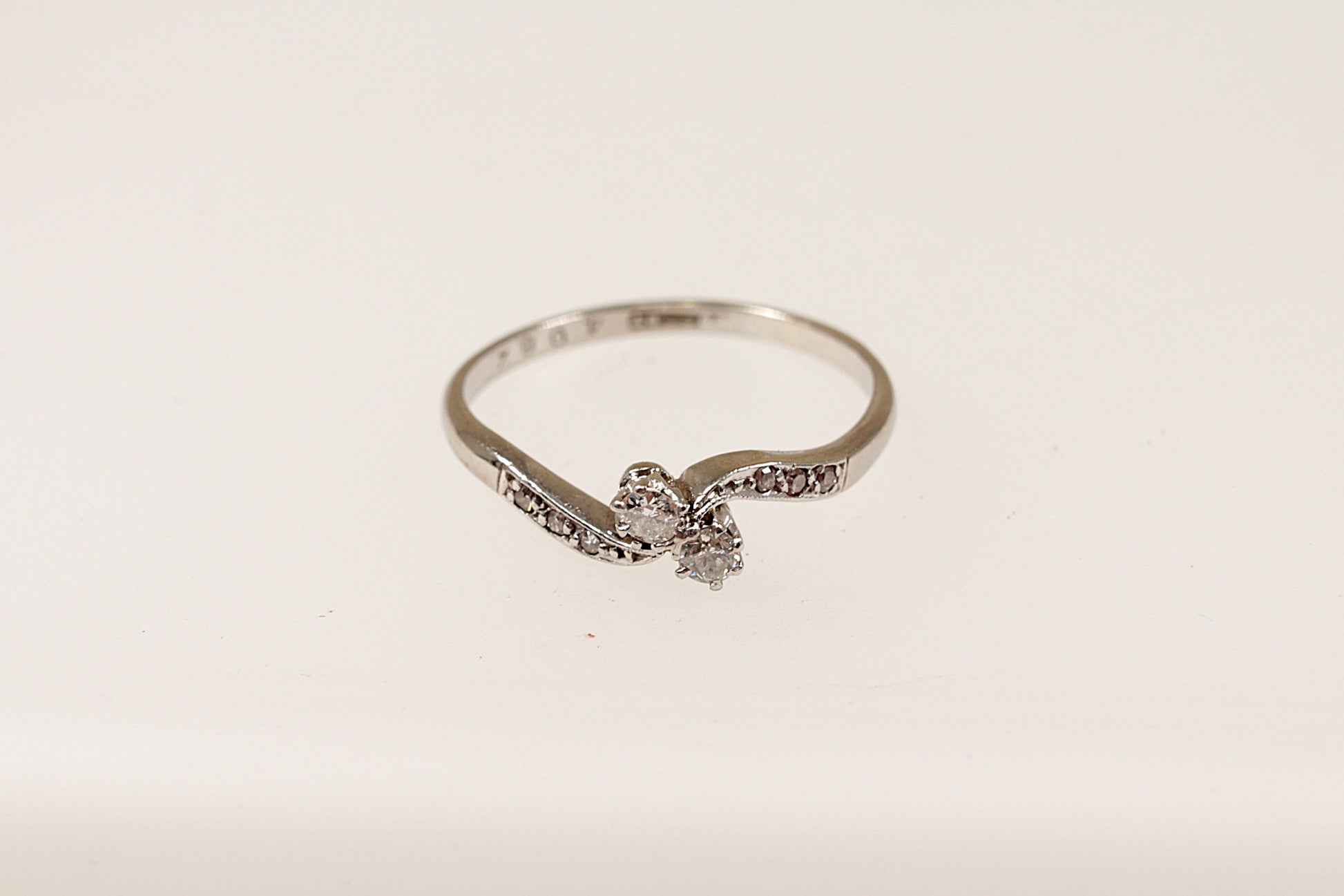 A vintage 18ct white gold and platinum diamond twist ring with a central pair of round diamonds and additional smaller diamonds on the shoulders, displayed against a white background.