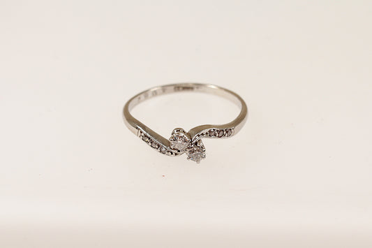A vintage 18ct white gold and platinum diamond twist ring with a central pair of round diamonds and additional smaller diamonds on the shoulders, displayed against a white background.