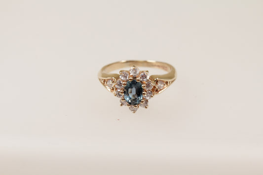 A 9ct gold cluster ring with a central blue topaz and surrounding cubic zirconia gemstones.