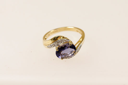 This 9ct Gold ring is a perfect blend of classic and contemporary design. The combination of the rich Iolite, shimmering Diamond accents, and the fluid twist design creates a piece that feels both timeless and distinctive. The centrepiece is the oval Blue Iolite that is claw set across the setting that gives a modern touch to the classic twist design. The Diamond accents are set along the twist. UK finger size M.