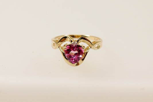 This charming 9ct Gold and heart shaped Pink Topaz ring is a romantic piece, perfect for that special occasion.
The delicate and elegant design showcases a Pink Topaz heart with a single diamond accent adding extra sparkle. Ornate Gold detailing surround the Topaz gemstone, this intricate craftsmanship adds texture and dimension to the ring enhancing its romantic appeal. UK finger size N.