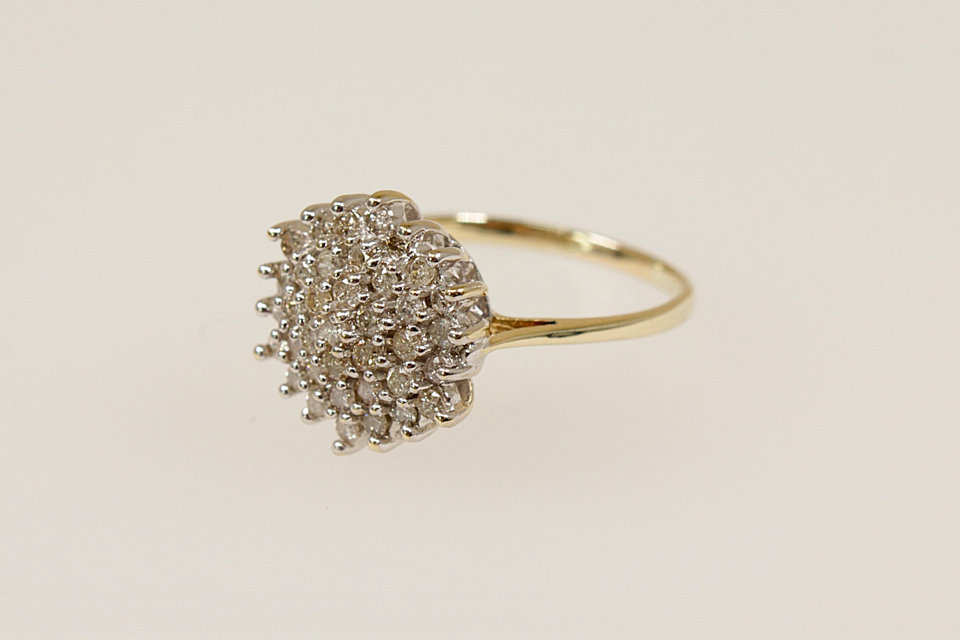 A 9ct gold diamond cluster ring with a high basket setting, showing a dome-shaped design with multiple diamonds arranged closely together. UK finger size L.