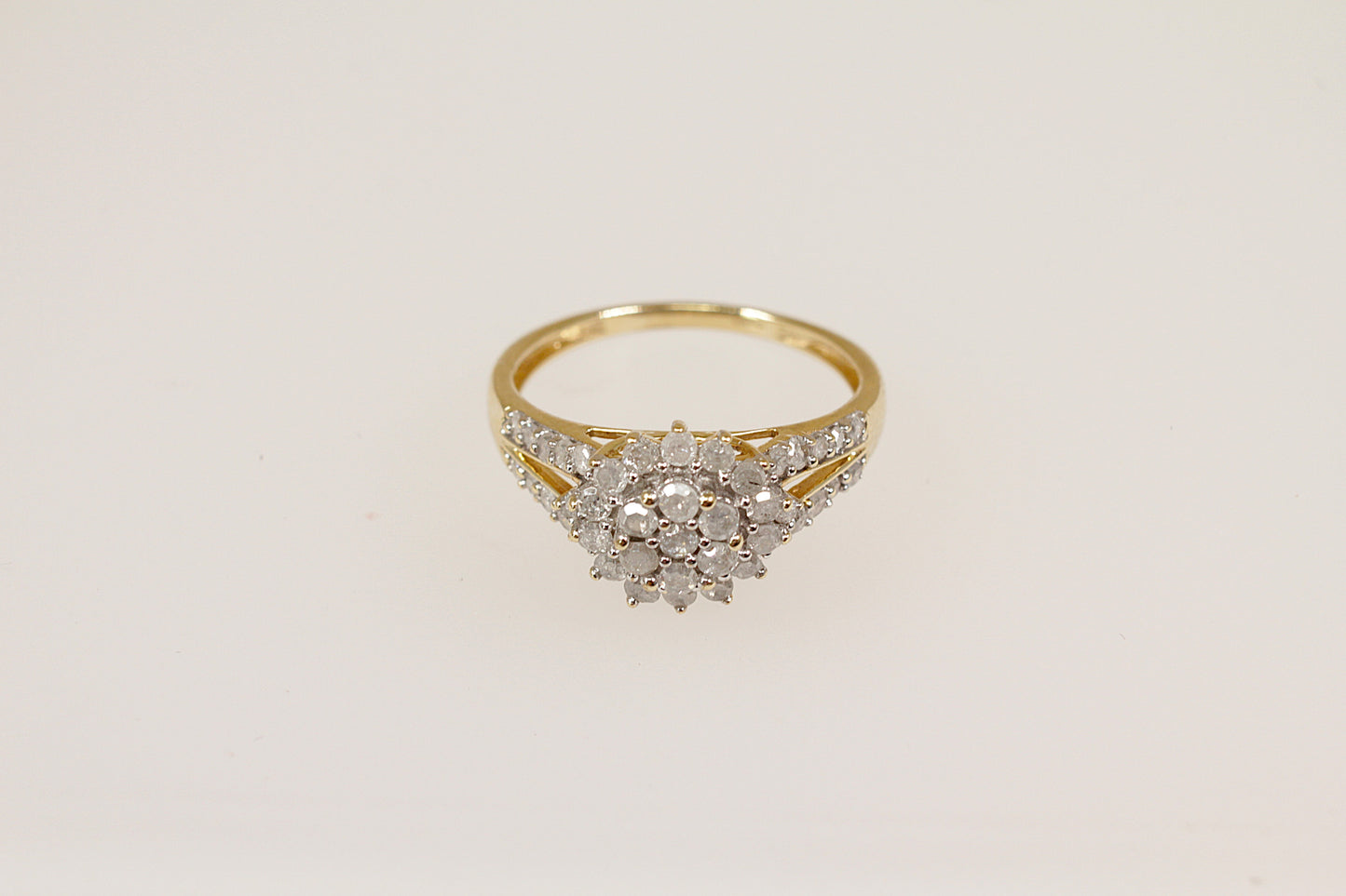 A 9ct gold diamond cluster ring with a two-tiered floral design, featuring a central flower-shaped cluster with sparkling diamonds and diamond accents on the shoulders.
