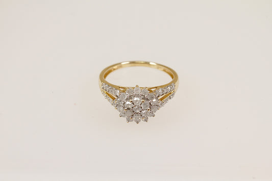 A 9ct gold diamond cluster ring with a two-tiered floral design, featuring a central flower-shaped cluster with sparkling diamonds and diamond accents on the shoulders.