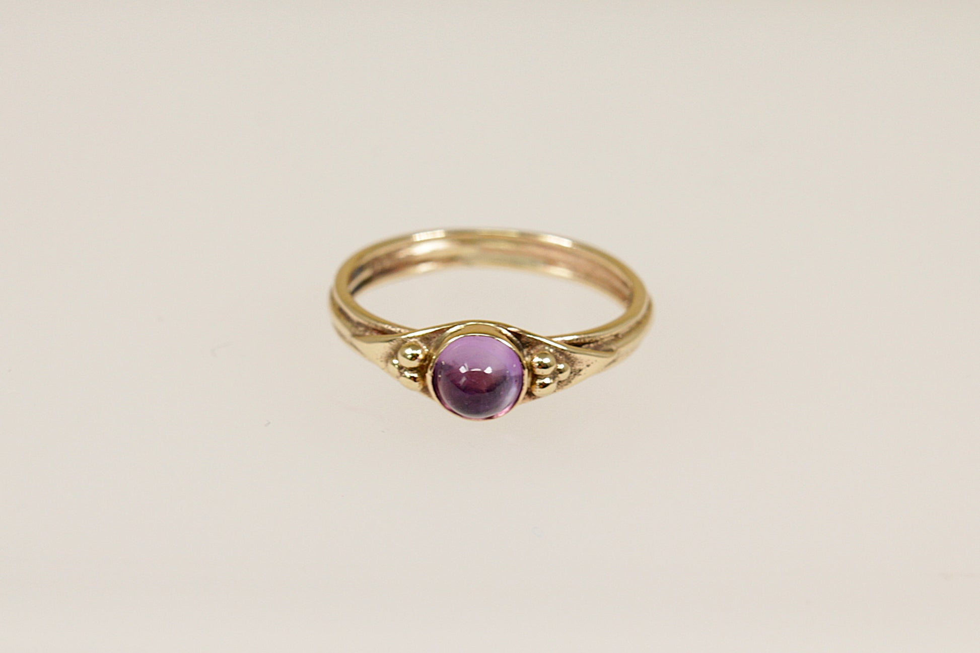 A vintage gold ring with a round amethyst cabochon gemstone set in a 9ct gold band with hallmarks interior.