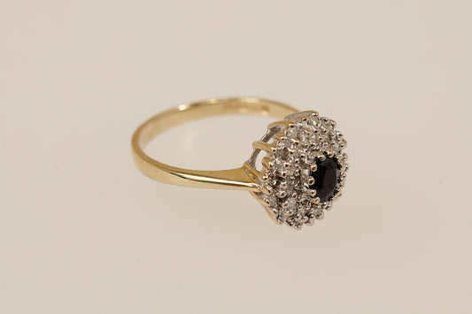 Gold Sapphire and Diamond cluster ring on a beige back ground.