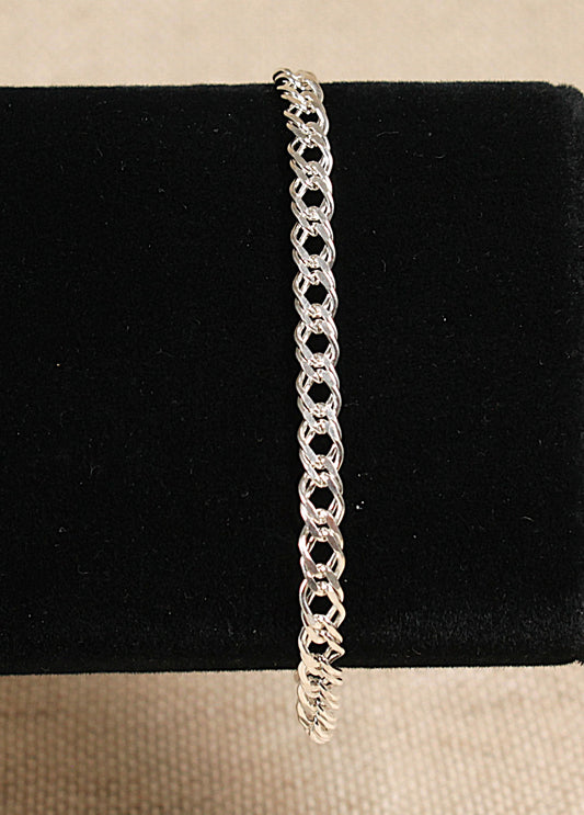 A silver chain link bracelet with a double link design and a lobster clasp fastening, displayed on a black stand.