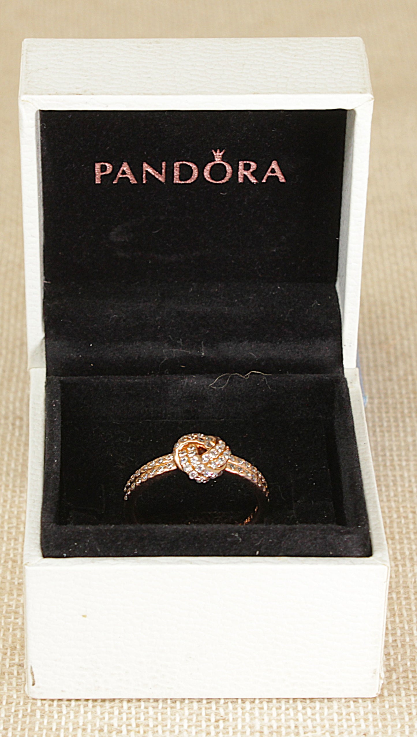 Pandora ring in a white box on a beige surface