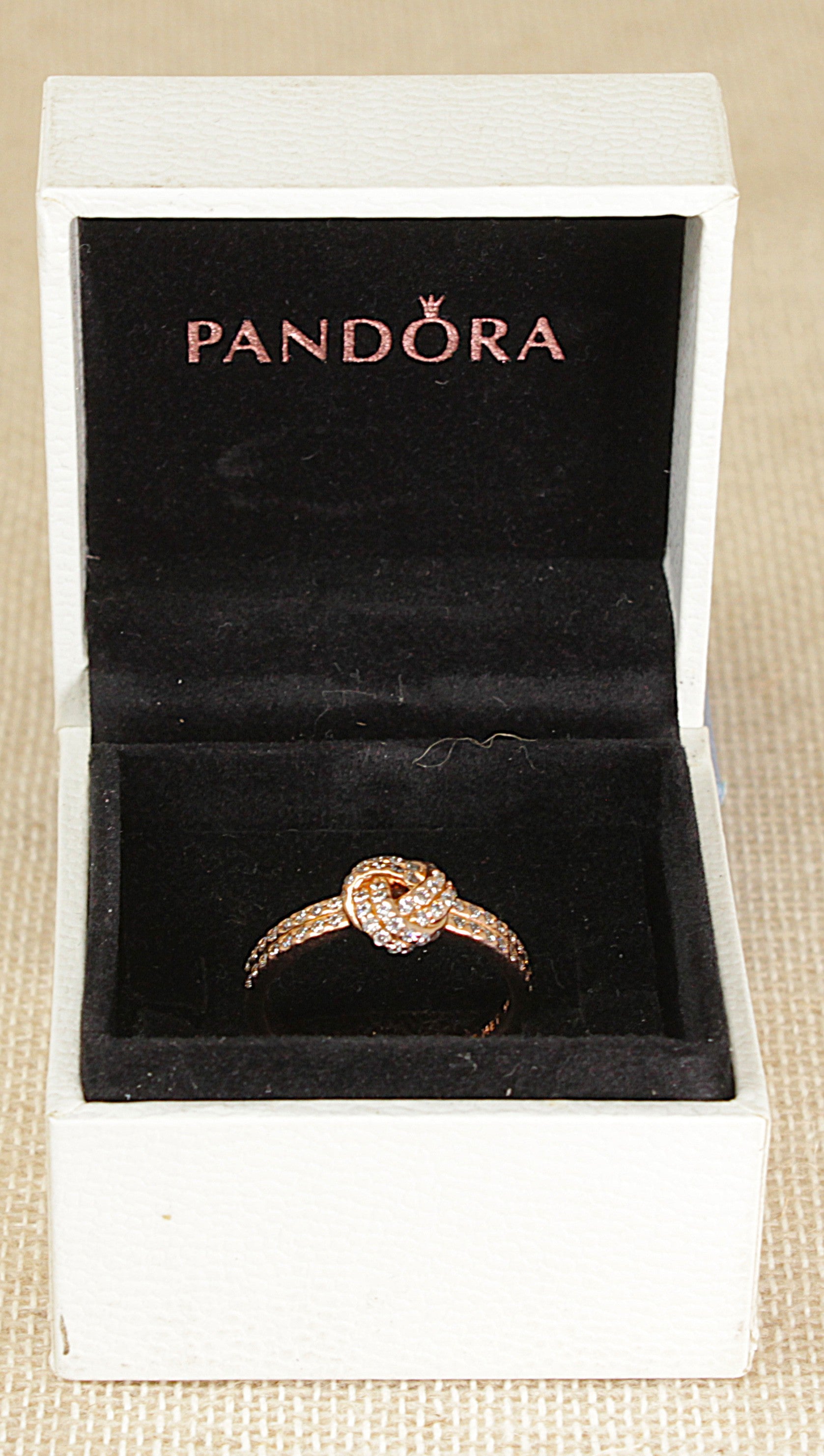 Pandora ring in a white box on a beige surface