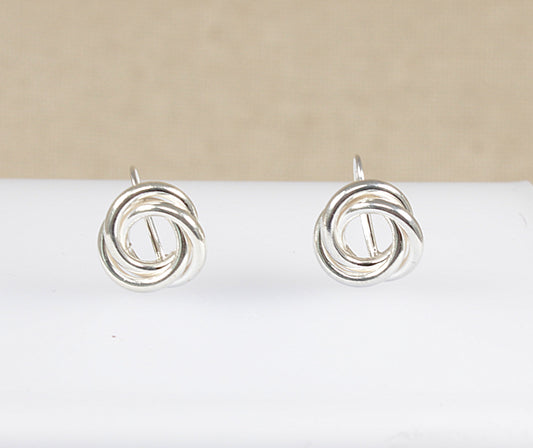 A pair of silver earrings with a round interlocking swirl design displayed against a beige background.