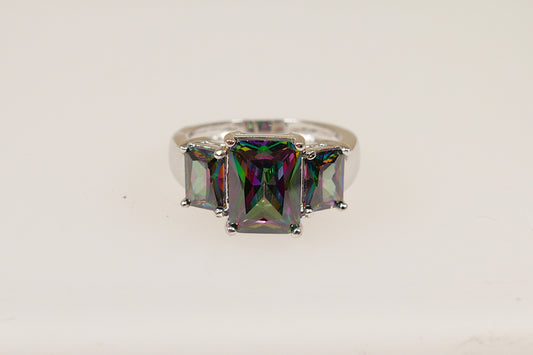 An elegant sterling silver ring with a central emerald cut mystic crystal gemstone, flanked by two smaller side stones, set in a crown setting.