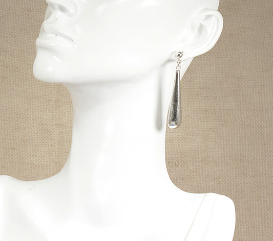 A pair of silver drop earrings displayed on a mannequin head.