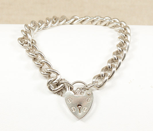 A silver curb link bracelet with a padlock clasp, laid out on a flat surface.