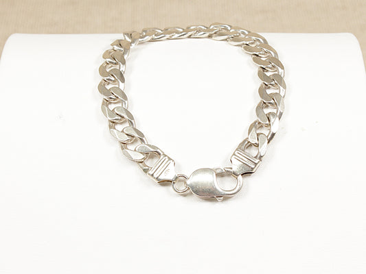 A silver flat curb link bracelet with a lobster clasp, displayed on a white surface.