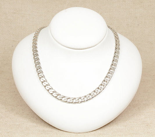 A silver curb link necklace displayed on a white mannequin bust against a beige background.
