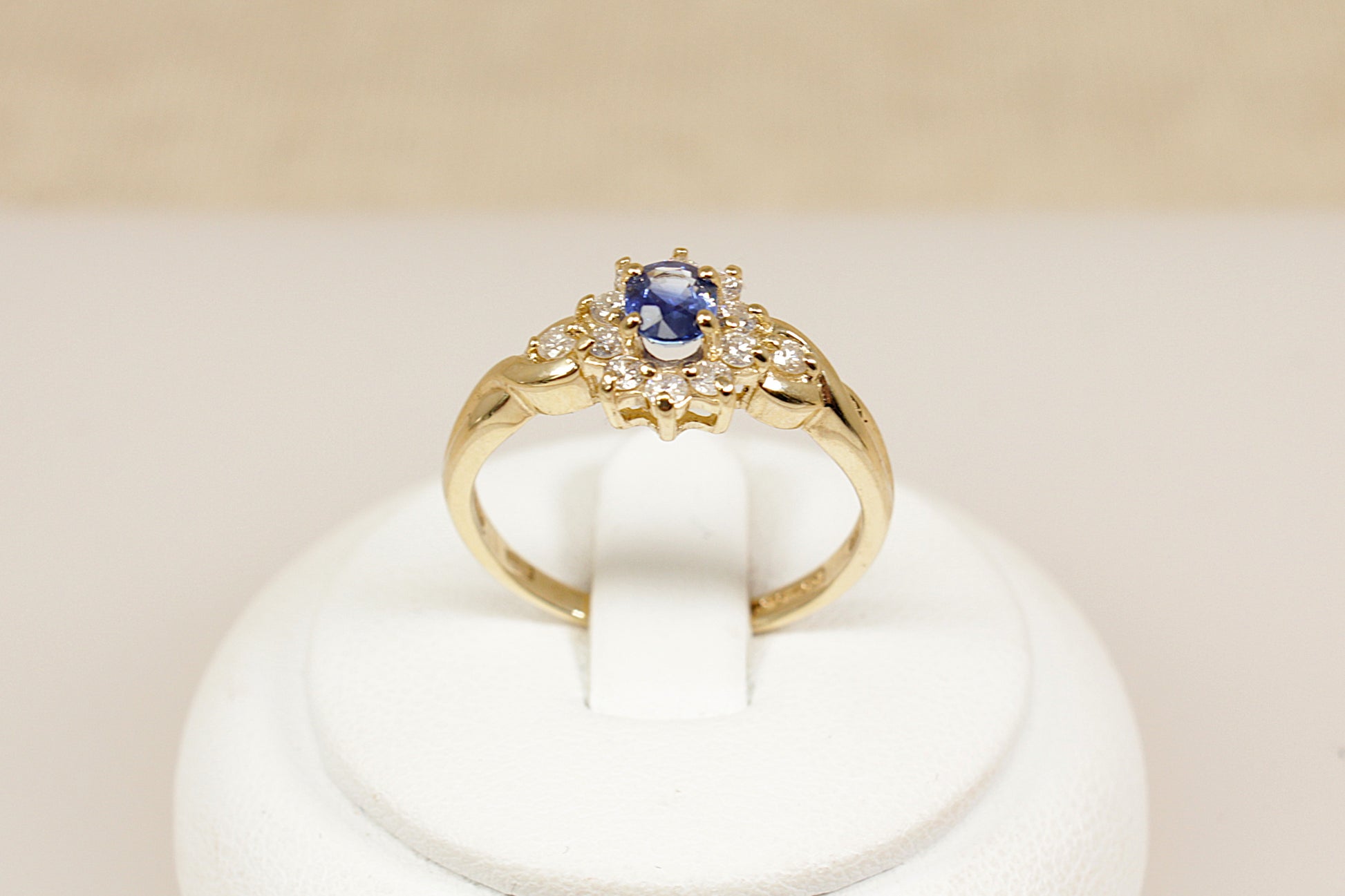 A timeless and elegant 9ct gold ring, inspired by the iconic Diana style. At its centre sits a rich oval sapphire, surrounded by a halo of 10 sparkling diamonds, creating a classic and regal look in a more delicate, wearable size, UK finger size P.