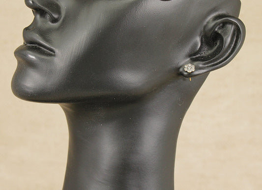 Black mannequin head with an earring on a beige background