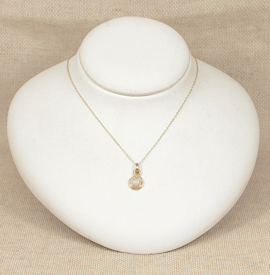 Gold necklace with a pendant on a white mannequin bust against a beige background