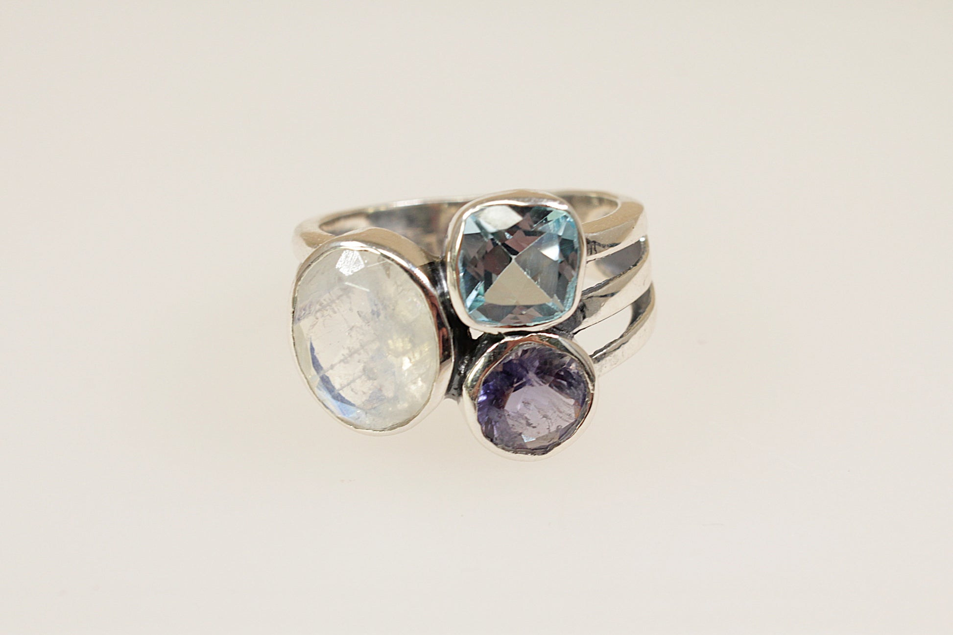 This Gorgeous Silver ring features 3 large faceted gemstones, Moonstone, Blue Iolite and Blue Topaz. Set in a stylish and elegant split band design, it is a bold and artistic statement piece. UK Finger size P.