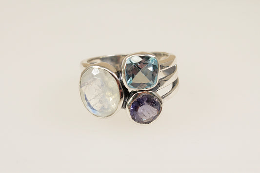 This Gorgeous Silver ring features 3 large faceted gemstones, Moonstone, Blue Iolite and Blue Topaz. Set in a stylish and elegant split band design, it is a bold and artistic statement piece. UK Finger size P.