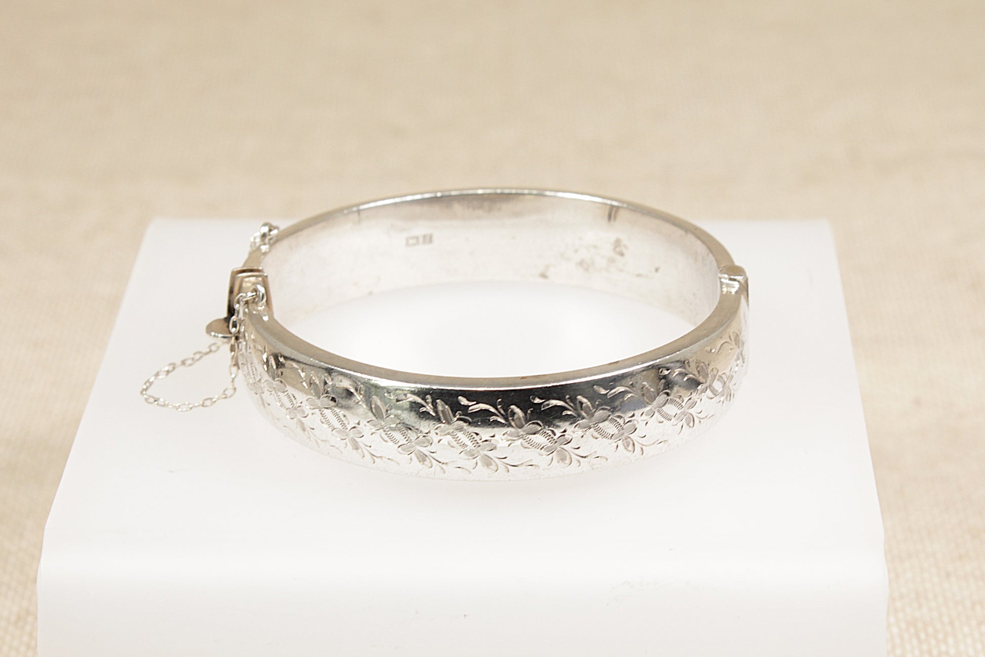 Vintage sterling silver nature inspired half etched floral design bracelet bangle the bangle has a safety chain and a secure clasp fastening it has Birmingham hallmarks with the date letter for 1967.
