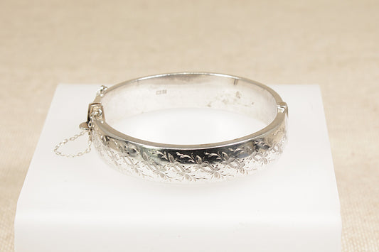 Vintage sterling silver nature inspired half etched floral design bracelet bangle the bangle has a safety chain and a secure clasp fastening it has Birmingham hallmarks with the date letter for 1967.