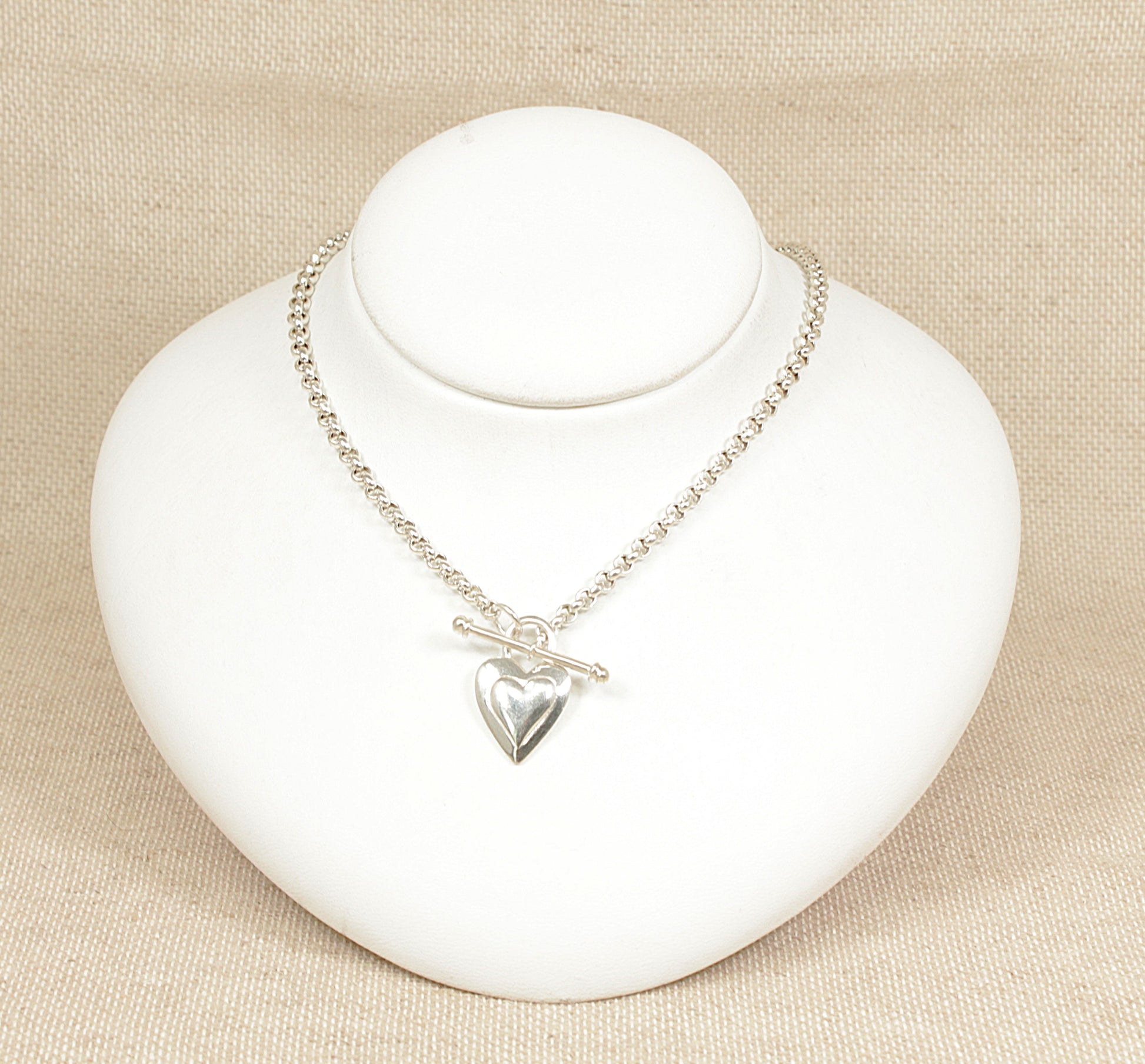 A sterling silver belcher chain necklace with a 'T' bar and heart-shaped fastener displayed on a white mannequin.