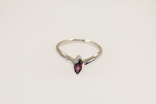A silver solitaire ring with a marquise cut garnet in a bezel setting, on a plain white background.