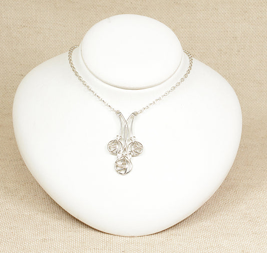 A silver necklet necklace with a geometric and floral design pendant, displayed on a white mannequin.
