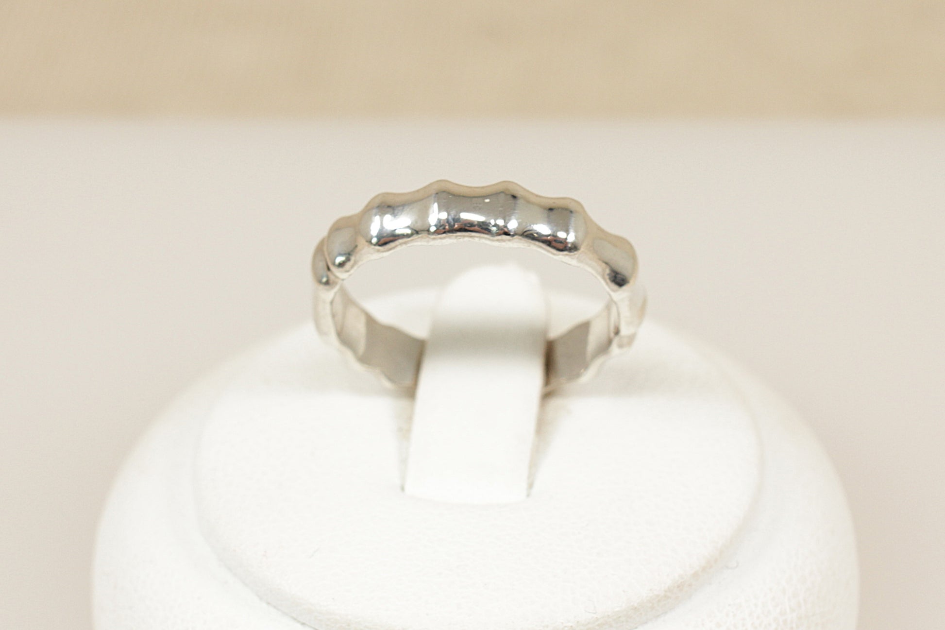 Silver ring on a white cushion with a beige background