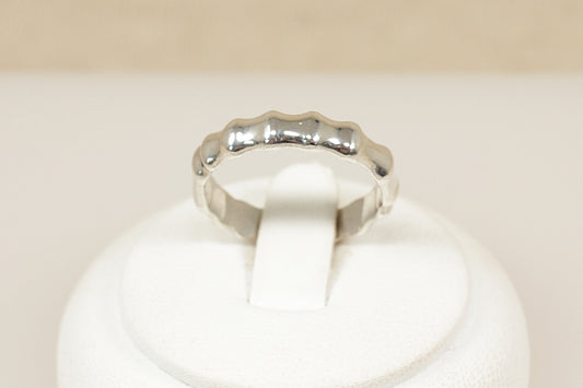 Silver ring on a white cushion with a beige background