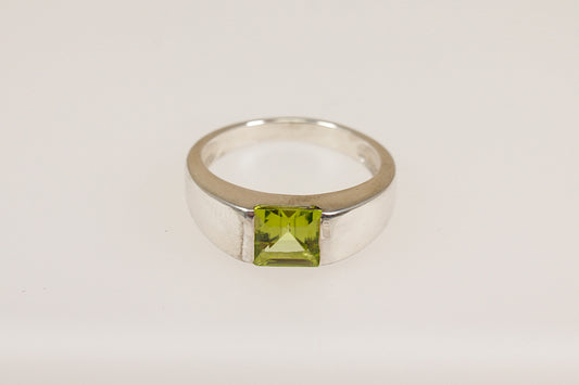 Silver ring with a green gemstone on a white background