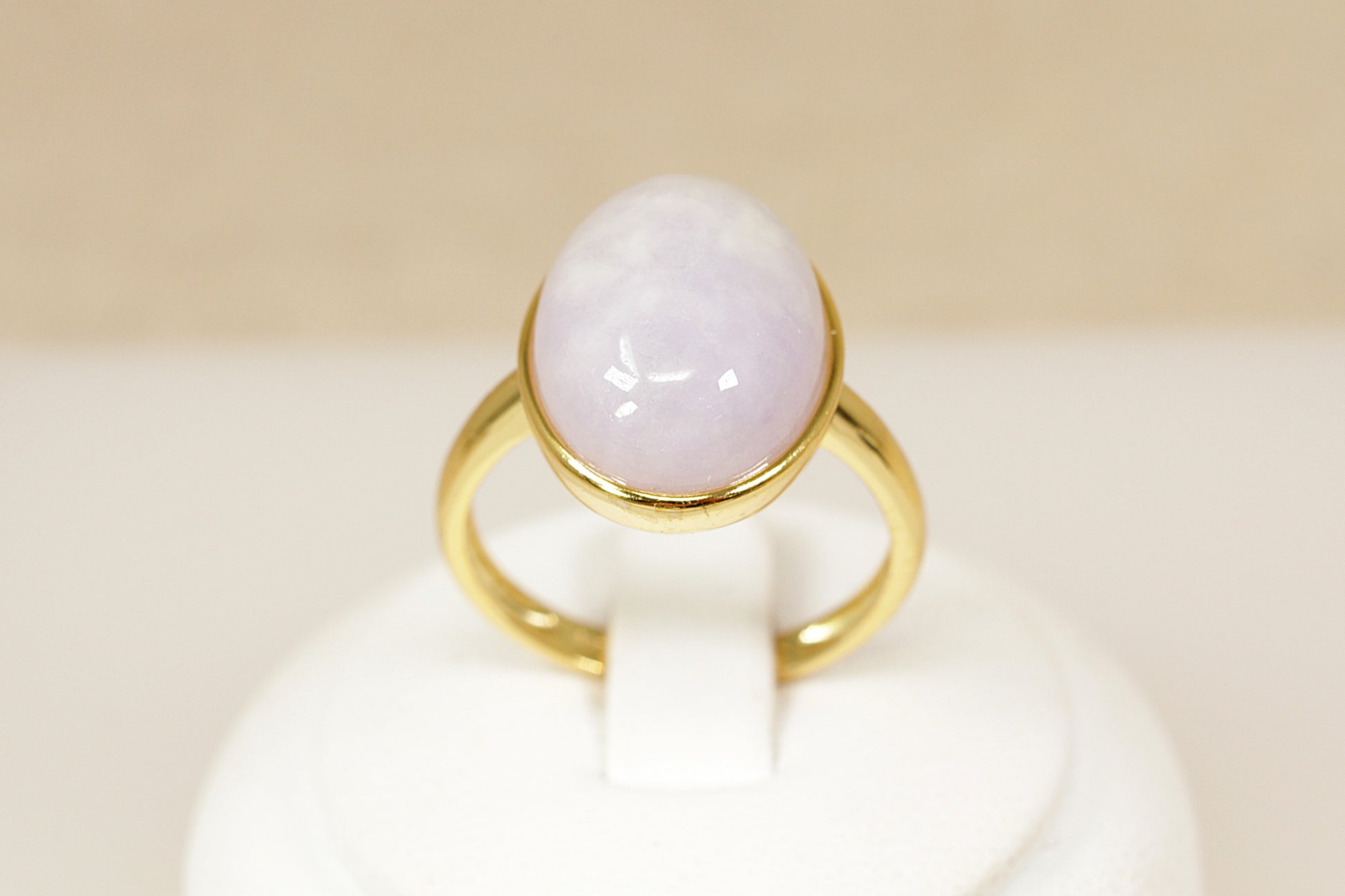Gold ring with a white stone on a beige background