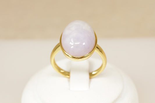 Gold ring with a white stone on a beige background