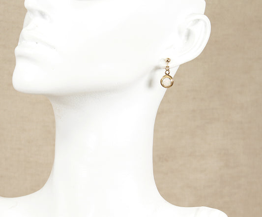 Gold earring on a beige background