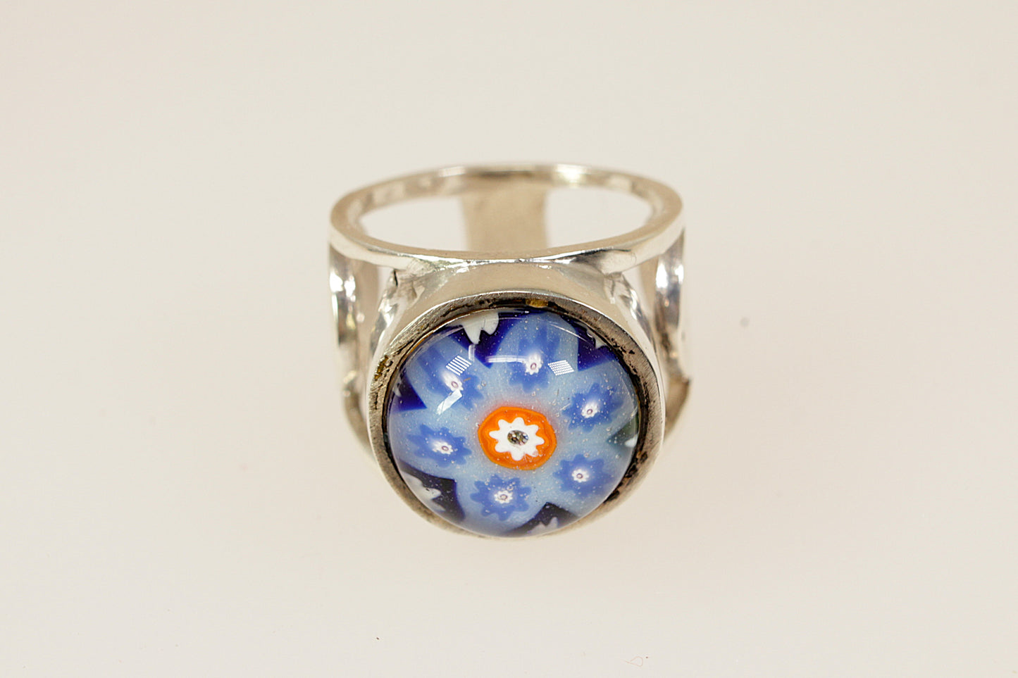 Silver ring with a blue floral design on a white background