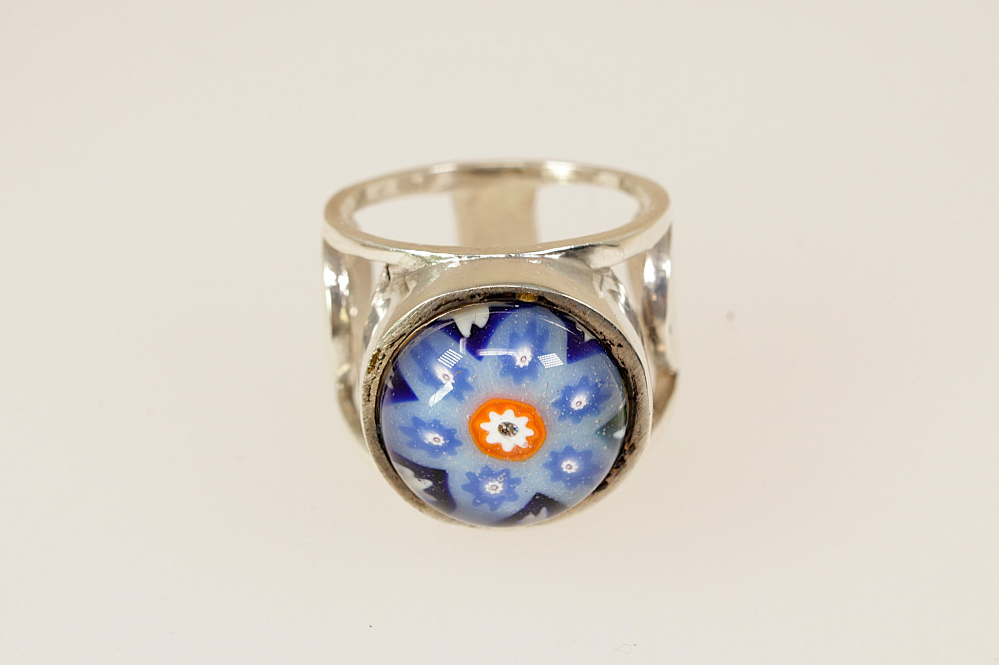 Silver ring with a blue floral design on a white background