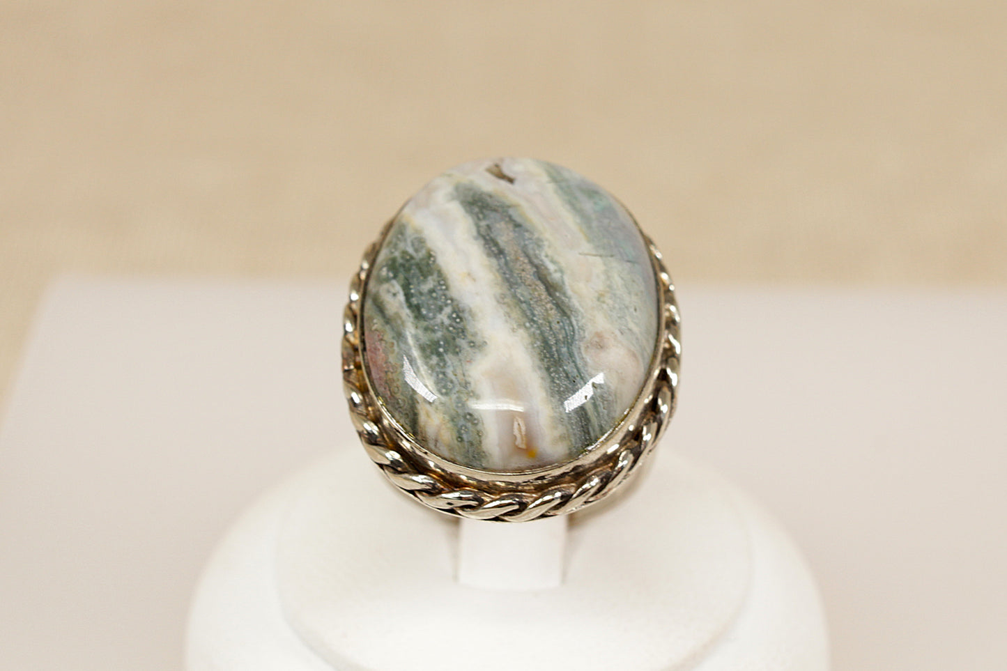 Ring with a stone on a white stand against a beige background