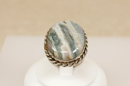 Ring with a stone on a white stand against a beige background