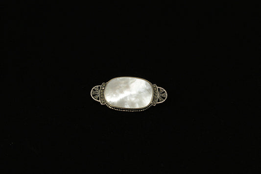 A beautifully crafted Sterling Silver brooch with an elegant Art Deco design, featuring a smooth oval mother of pearl centrepiece that shimmers with subtle iridescence. At each end of the centre MOP is a curved silver band set with glittering marcasite stones, leading into a fan-shaped design adorned with additional marcasite for extra vintage sparkle.