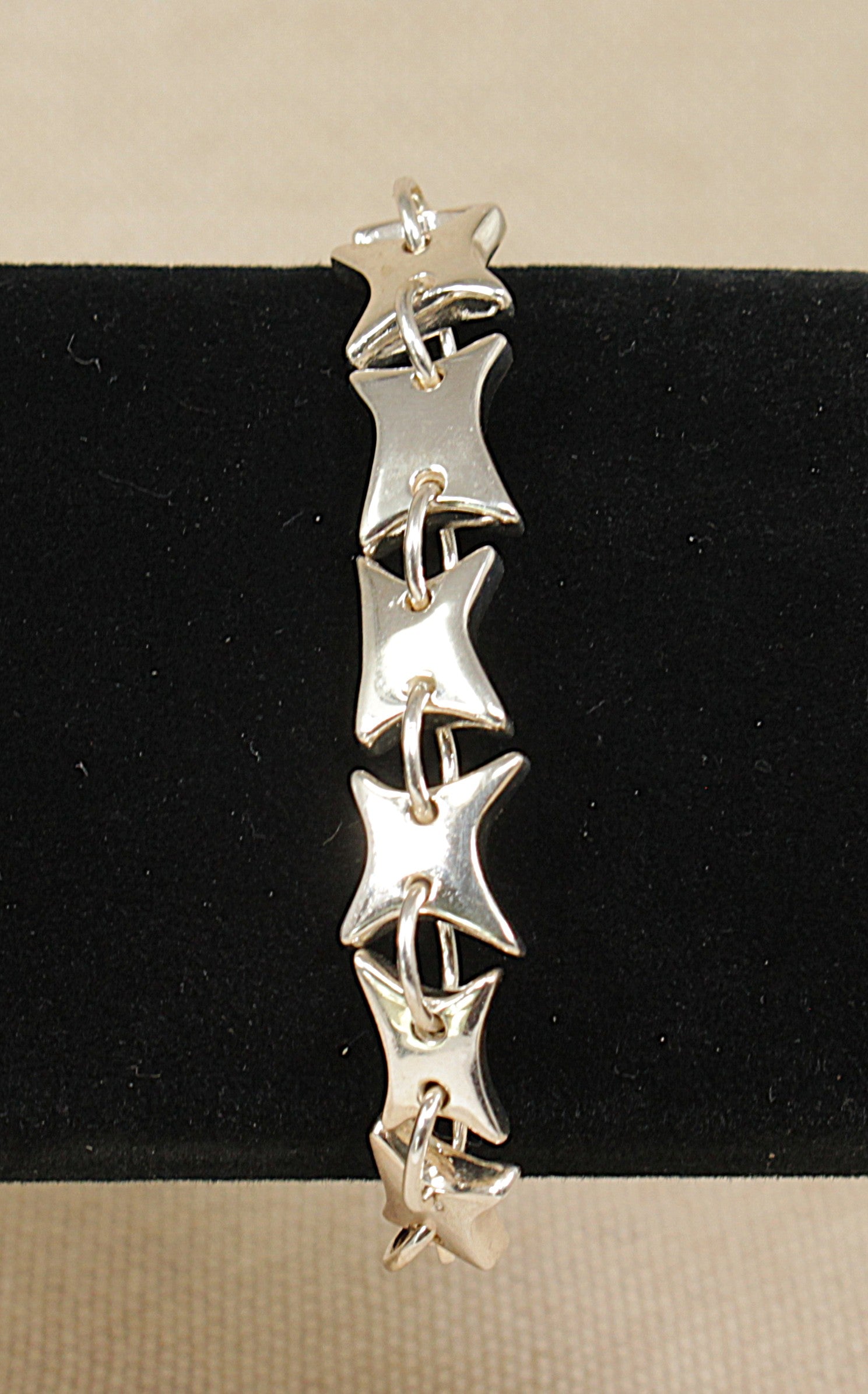 Silver star-shaped bracelet on a black and beige background