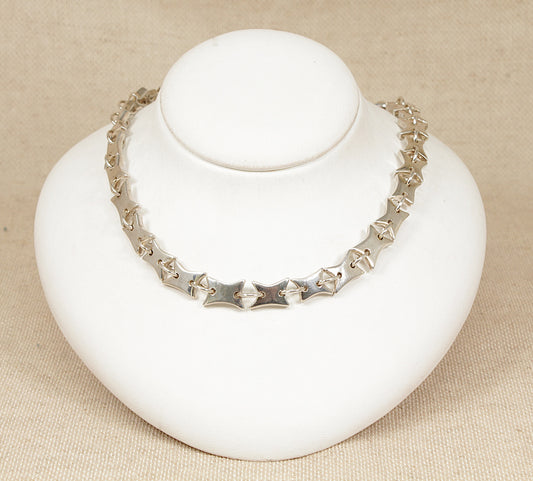 Silver necklace on a white mannequin bust against a beige background