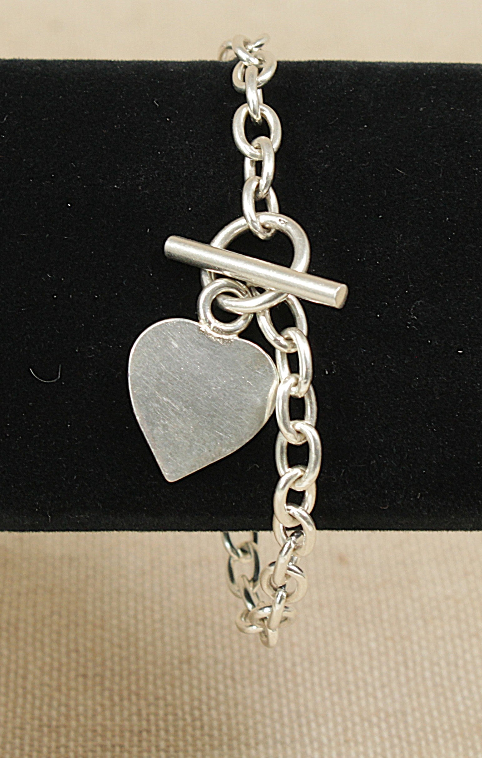 Silver bracelet with a heart-shaped charm on a black background