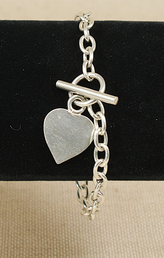 Silver bracelet with a heart-shaped charm on a black background
