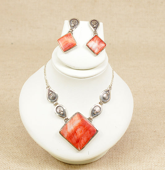 Necklace and earrings set with orange / fire square stones on a white stand.