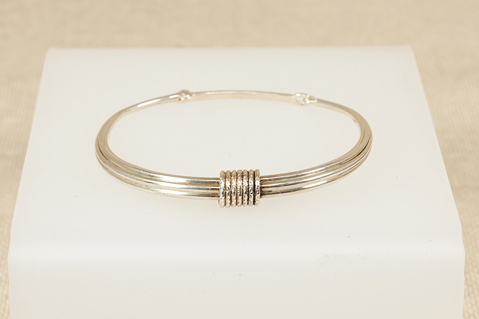 Silver bracelet on a white box with a beige background