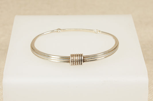 Silver bracelet on a white box with a beige background