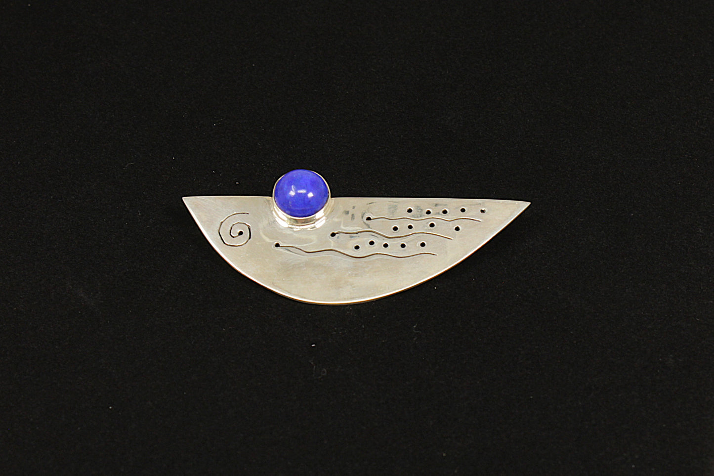 Silver pendant with a blue gemstone on a black background