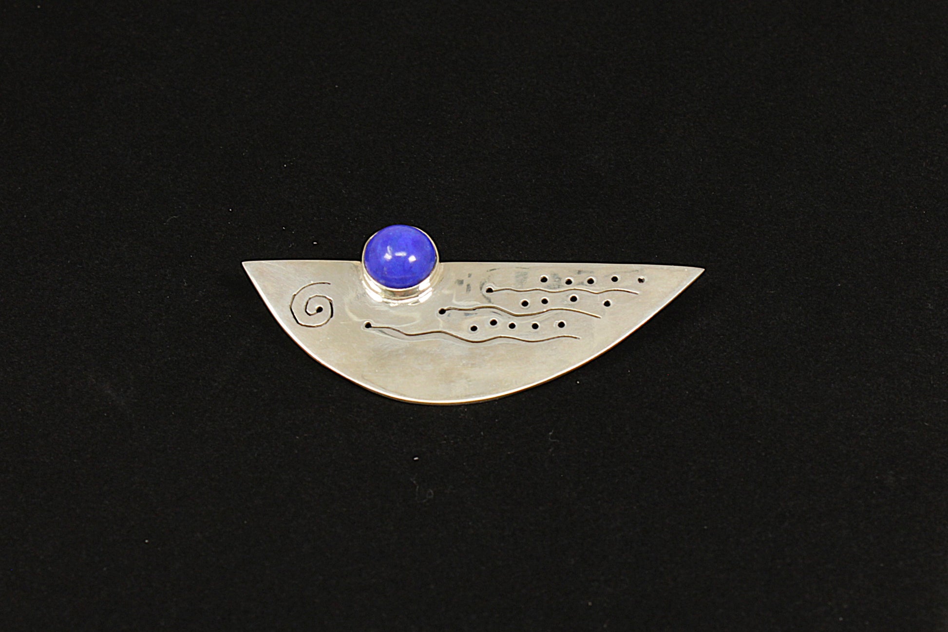 Silver pendant with a blue gemstone on a black background