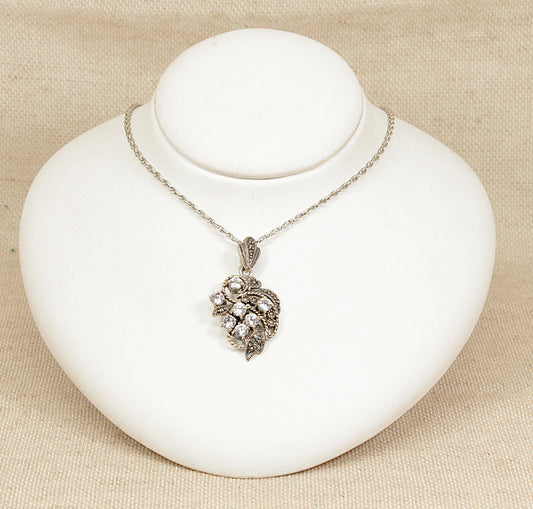 A beautifully ornate vintage sterling Silver pendant and chain set, inspired by the flowing elegance of Art Nouveau design. The pendant features an intricate floral display, adorned with seven round sparkling crystals.